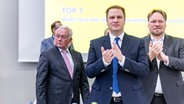 Christopher Vogt (FDP, m.), Vorsitzender seiner Partei im schleswig-holsteinischen Landtag, Oliver Kumbartzky (FDP, r.), Landesvorsitzender seiner Partei, gratulieren Wolfgang Kubicki (FDP, l.) zu seiner Wahl zum Spitzenkandidaten der FDP für die Bundestagswahl. © dpa-Bildfunk Foto: Axel Heimken