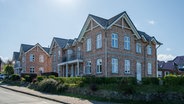 Eine Straße mit Gebäuden für Ferienwohnungen in Norddorf auf Amrum. © IMAGO / penofoto 