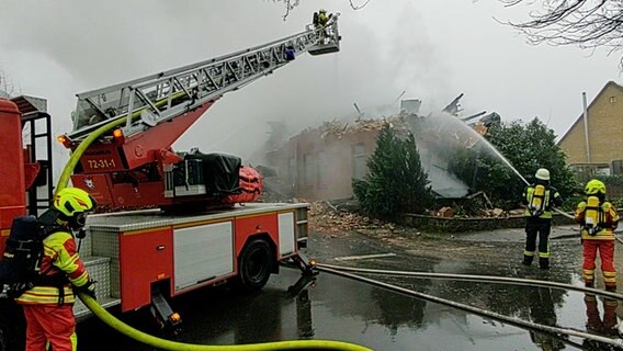 Einsatzkräfte der Feuerwehr löschen mit einem Feuerwehrschlauch ein Haus in Wohlde. © NDR 