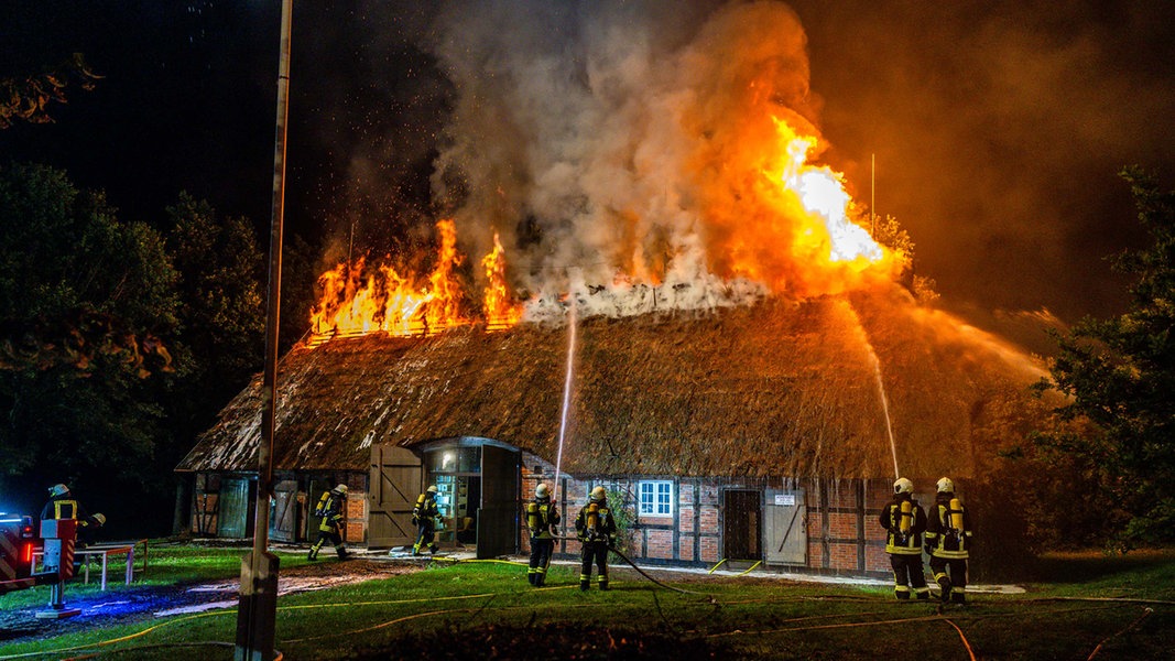 Einsatzkräfte der Feuerwehr löschen ein in Brand geratenes historisches Reetdachhaus im Landschaftsmuseum Angeln in Unewatt.