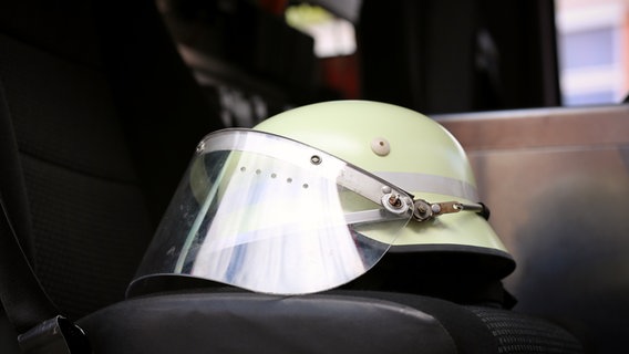 Ein Schutzhelm liegt auf dem Autositz eines Feuerwehrautos. © NDR Foto: Pavel Stoyan