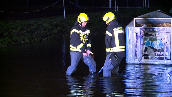 Zwei Feuerwehrmänner versuchen einen Gullideckel nach einem Starkregen zu befreien. © Florian Sprenger 