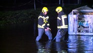 Zwei Feuerwehrmänner versuchen einen Gullideckel nach einem Starkregen zu befreien. © Florian Sprenger 