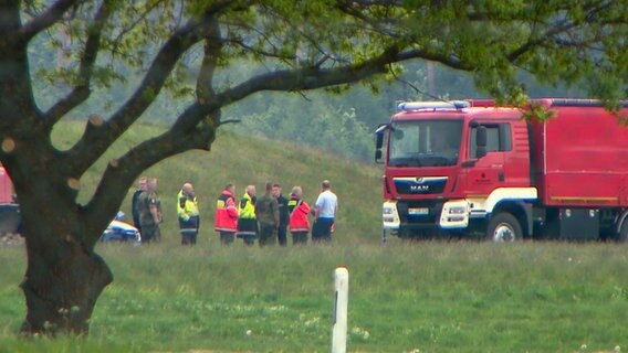 Einsatzkräfte der Polizei und Feuerwehr stehen an dem Unglücksort auf Bundeswehrflugplatz in Hohn, wo vorher ein Flugzeug abgestürzt ist. © Daniel Friederichs Foto: Daniel Friederichs