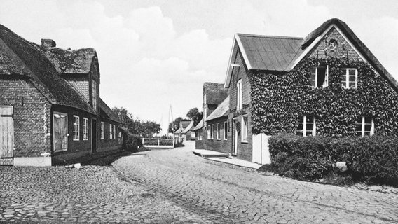 Ein Schwarz-Weiß-Bild zeigt eine historische Straßenansicht von Oldsum auf Föhr. © Ferring Stiftung 