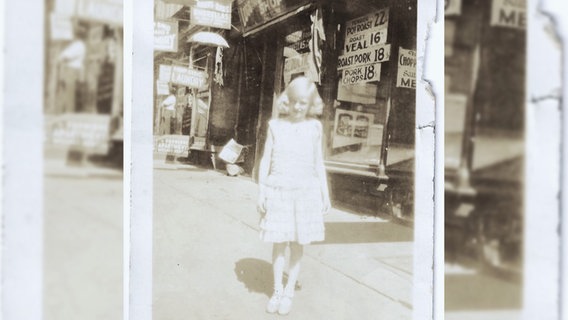 Ein Schwarz-Weiß-Foto zeigt die 7-jährige Inge vor einigen Geschäften in New York. © Bente Faust 