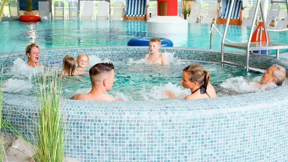 In einem großen Whirlpool im Inneren der Fördeland-Therme baden mehrere Gäste. © Fördeland Therme 