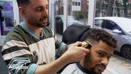 Ein Friseur schneidet einem Kunden die Haare. © NDR 