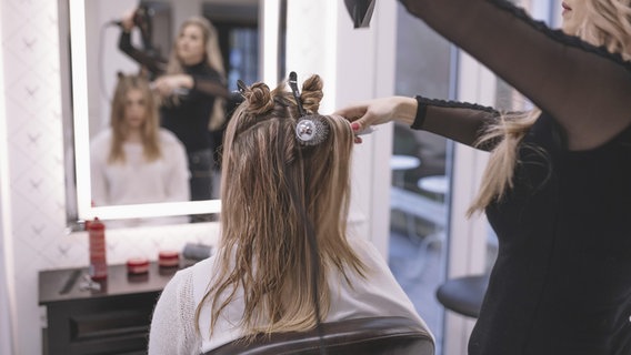 Eine Friseuse kämmt und föhnt einer Kundin die Haare. © picture alliance / imageBROKER Foto: Oleksandr Latkun