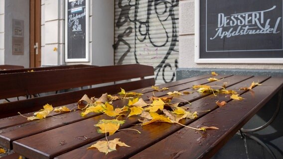 A table set in front of a closed restaurant with leaves on the table.  © imago images / Seeliger 