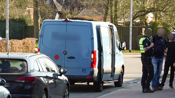 Polizeibeamte stehen neben einem blauen Geldtransporter nach einem Überfall in Reinbek. © NEWS5 