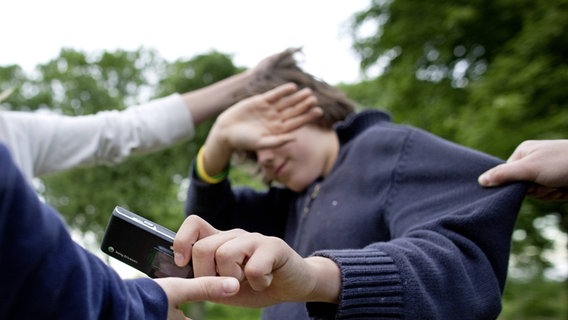 Ein Junge wird an den Haaren gezogen und gibt sein Handy einer anderen Person. © Thomas Koehler Foto: Thomas Koehler