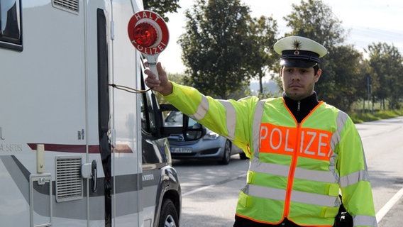 Ein Polizist hält seine Kelle hoch, um Fahrzeuge für eine Passkontrolle aus dem Einreiseverkehr zu ziehen. © dpa-Bildfunk Foto: Jörn Hüneke/dpa