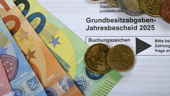 Euro-Münzen und Euro-Scheine liegen auf eine Grundbesitzabgaben-Jahresbescheid 2025. © picture alliance / imageBROKER Foto: Michael Weber