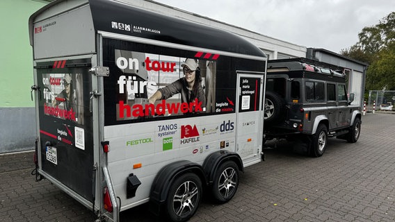 Julia Spielvogels Camper steht mit dem Werkzeug-Anhänger auf dem Schulparkplatz. © NDR Foto: Karen Münster