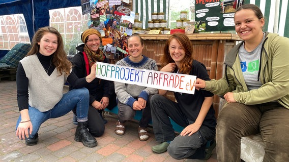 Mehrere Personen posieren mit einem Banner, auf dem Banner steht: Hofprojekt Arfrade e.V. © NDR Foto: Torsten Creutzburg
