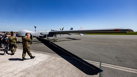 Eine Drohne vom Typ German Heron TP der Bundeswehr wird nach dem ersten offiziellen Flug über Norddeutschland von Soldaten und Pressevertretern umringt. © dpa-Bildfunk Foto: Axel Heimken