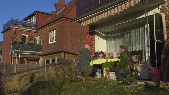 Die Familienbesucherin von "Hippy" sitzt mit Manuela Böse und ihrer Tochter am Tisch auf der Terrasse. © NDR 