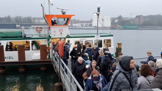 Mehrere Menschen stehen in einer Schlange vor einer Fähre über den Nord-Ostsee-Kanal. © NDR 