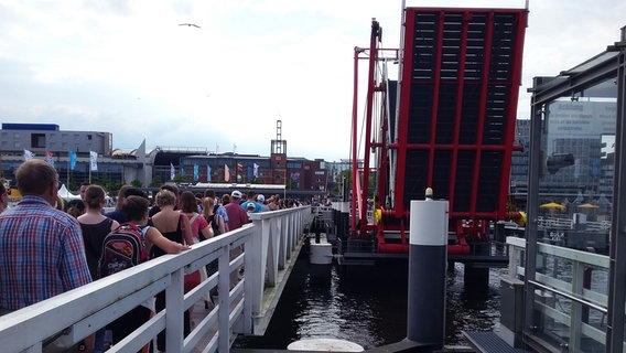 Die Hörnbrücke in Kiel ist nach oben gezogen worden, so dass die Besucher der Kieler Woche sie nicht mehr überqueren können. Stattdessen laufen Sie über eine schmale Brücke neben an. © NDR Foto: Nikolai Hotsch