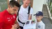 Holstein Kiels Trainer Marcel Rapp gibt einem jungen Fan ein Autogramm. © NDR Foto: Samir Chawki