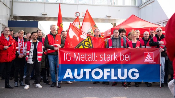 Menschen demonstrieren mit einem Banner "IG Metall: stark bei Autoflug". © NDR Foto: Ole ter Wey