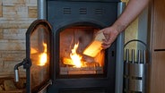 Ein Holzofen in einem Wohnzimmer in Betrieb. © picture alliance / M.i.S. Foto: Bernd Feil