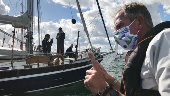 Leiter der Segelregatta zur Kieler Woche Dirk Ramhorst (rechts) spricht mit anderen Seglern auf ihren Booten. © NDR Foto: Frauke Hain