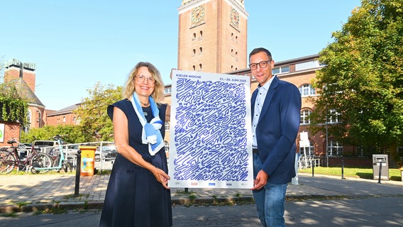 Die zweite stellvertretende Stadtpräsidentin der Landeshauptstadt Kiel, Antje Möller-Neustock, und der Leiter des Kieler-Woche-Büros, Philipp Dornberger präsentieren das Kieler Woche Design für 2025. © Landeshauptstadt Kiel 