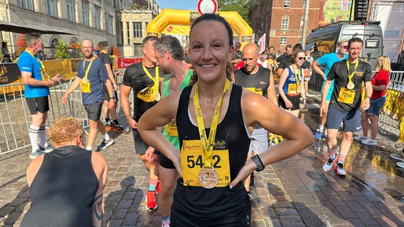 Eine Frau steht nach einem Marathon im Ziel © NDR Foto: Ole ter Wey