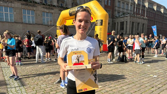 Eine Frau hält nach einem Marathon eine Urkunde in der Hand © NDR Foto: Ole ter Wey