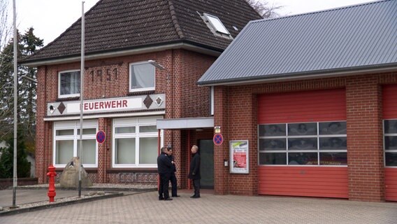 Drei Männer stehen vor dem Feuerwehrhaus der Gemeinde Kisdorf. © NDR 