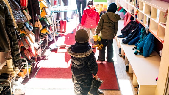 Kinder einer Kita ziehen sich an, um im Außengelände zu spielen. © picture alliance/dpa Foto: Axel Heimken