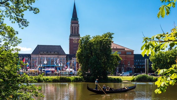 Kiels Rathaus zur Kieler Woche 2024 mit dem Internationalen Markt, in der Wasserfläche vor dem Rathaus fährt ein Gondoliere mit einem Boot © IMAGO Foto: penofoto