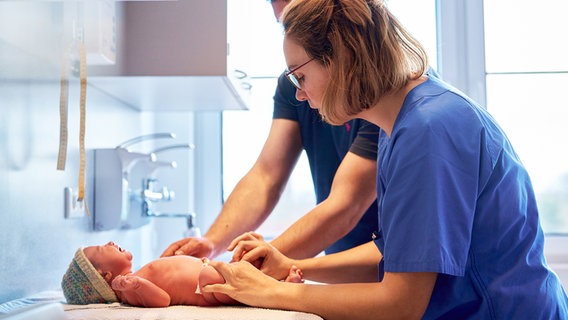 Ein Pfleger und eine Pflegerin behandeln einen Säugling. © Klinik Husum Foto: Lars Franzen