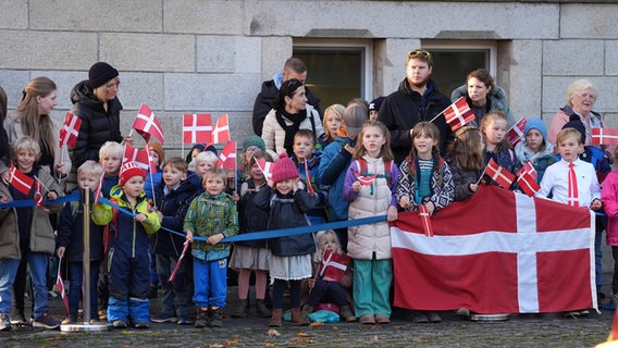 Kinder mit dänischen Flaggen warten auf die Ankunft von König Frederik X. von Dänemark und Königin Mary von Dänemark vor dem Gästehaus der Schleswig-Holsteinischen Landesregierung. © dpa Foto: Marcus Brandt