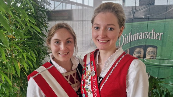 Zwei Frauen in roter Tracht stehen nebeneinander. Sie sind die Dithmarscher Kohlregentinnen. © NDR Foto: Oliver Kring