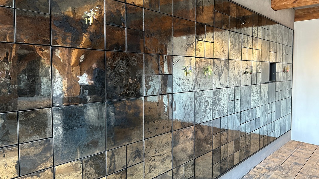 Hinter einer Wand aus kunstvoll gestalteten Glasplatten befinden sich Urnenfächer.
