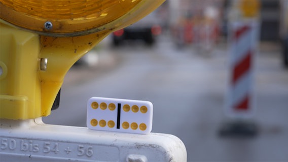 Ein Dominostein liegt auf einer Verkehrsbake. © NDR Foto: NDR