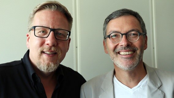 Jan Malte Andresen (l.) und Christian Kuhnt, der Intendant des Schleswig-Holstein Musik Festivals, stehen nebeneinander vor einer Wand und lächeln. © NDR Foto: Samir Chawki