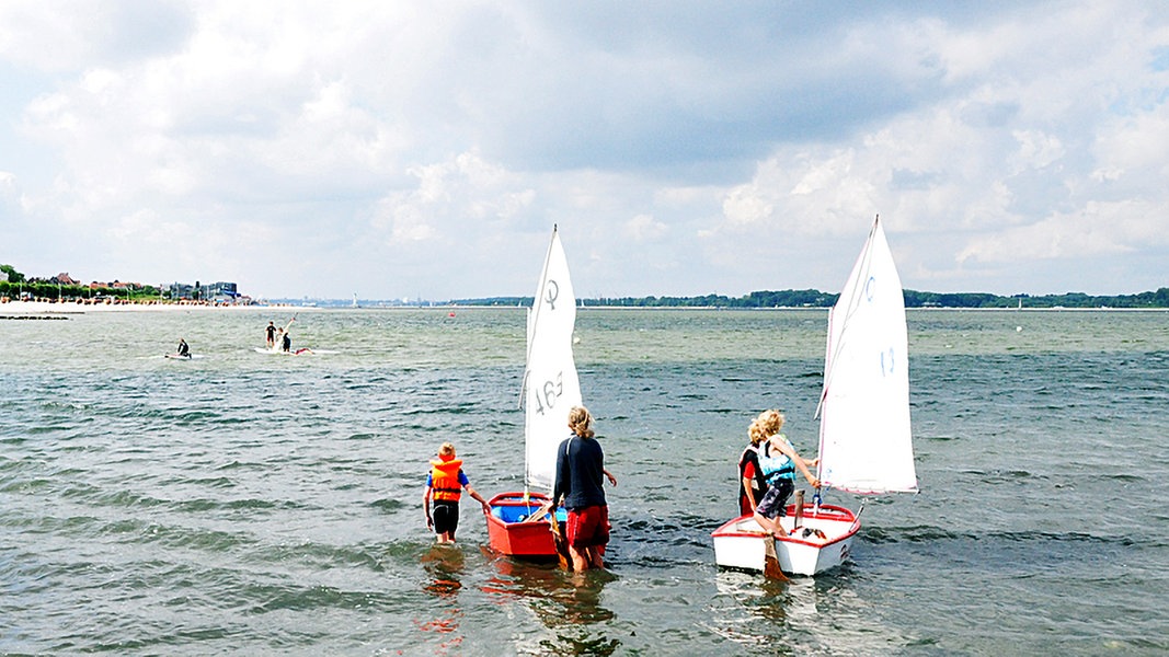 Kinder segeln in Optimisten am Strand von Laboe bei Kiel.
