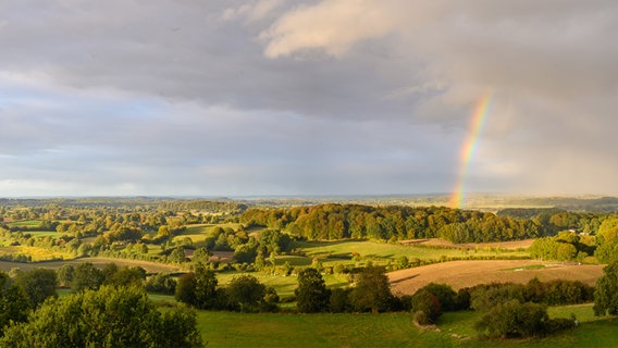 Ein Regenbogen erstreckt sich über eine Landschaft in Schleswig-Holstein. © IMAGO / Depositphotos 