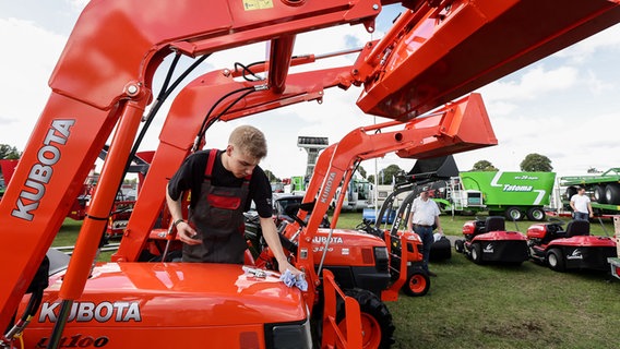 Ein junger Mann putzt auf der Landwirtschaftsmesse Norla eine landwirtschaftliche Maschine. © dpa-Bildfunk Foto: Ulrich Perrey