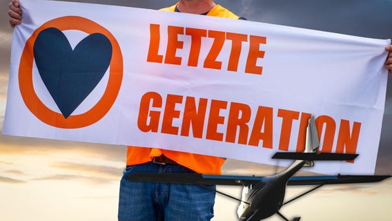 Ein Aktivist mit einer Warnweste und einem Banner mit der Aufschrift "Letzte Generation". © picture alliance / CHROMORANGE | Michael Bihlmayer Foto: Michael Bihlmayer