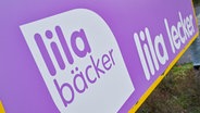 Ein Schild mit der Aufschrift "Lila Bäcker - Lila lecker". © picture alliance/dpa | Patrick Pleul Foto: Patrick Pleul