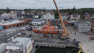 Ein Lotsenboot wird von einem Kran gehoben. © NDR 