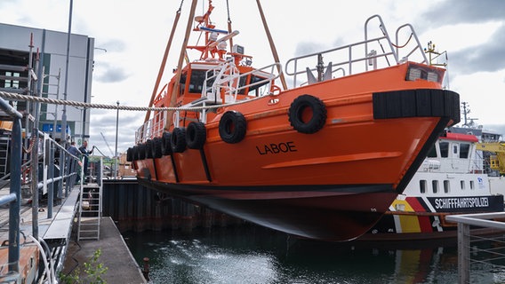 Das Lotsenboot mit dem Namen Laboe wird gerade aus dem Wasser geholt und schwebt in der Luft. © NDR Foto: Dominik Dührsen