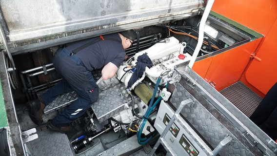 Ein Mann lehnt sich über den Dieselmotor, um gegebenenfalls Reparaturen vorzunehmen. © NDR Foto: Dominik Dührsen