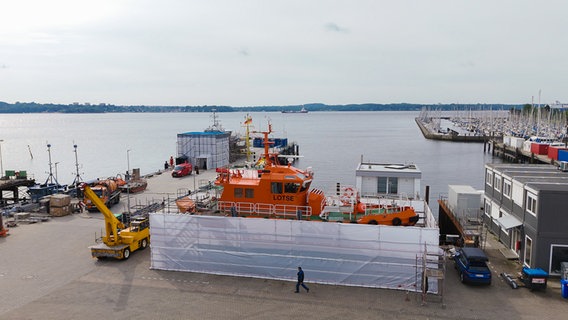 Das Lotsenboot wurde an Land gebracht und mit einem Bauzaun zum Arbeiten umringt. © NDR Foto: Dominik Dührsen