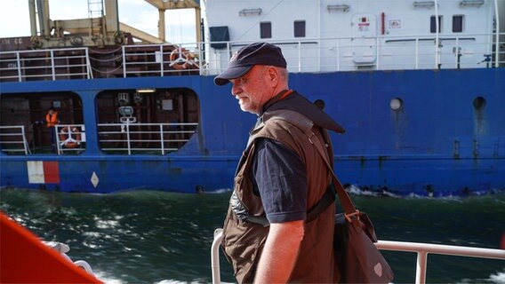 Ein Lotse mit Kappe geht über ein Schiff. © NDR Foto: Dominik Dührsen